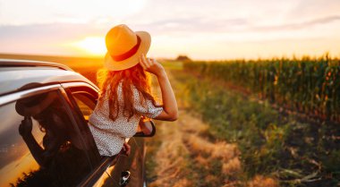 Young happy woman leaning out of the car window enjoying travel. The concept of active lifestyle