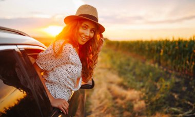 Arabasının camından sarkıp seyahatin tadını çıkaran genç ve mutlu bir kadın. Aktif yaşam tarzı kavramı