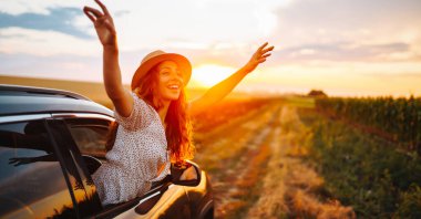 Arabasının camından sarkıp seyahatin tadını çıkaran genç ve mutlu bir kadın. Aktif yaşam tarzı kavramı