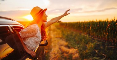 Arabasının camından sarkıp seyahatin tadını çıkaran genç ve mutlu bir kadın. Aktif yaşam tarzı kavramı