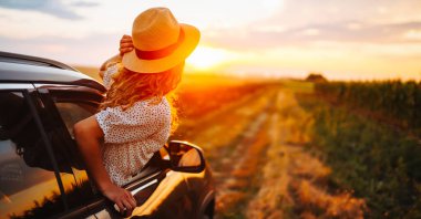 Arabasının camından sarkıp seyahatin tadını çıkaran genç ve mutlu bir kadın. Aktif yaşam tarzı kavramı