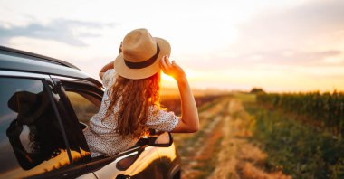 Arabasının camından sarkıp seyahatin tadını çıkaran genç ve mutlu bir kadın. Aktif yaşam tarzı kavramı
