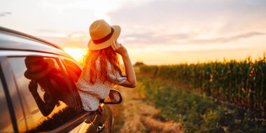 Arabasının camından sarkıp seyahatin tadını çıkaran genç ve mutlu bir kadın. Aktif yaşam tarzı kavramı