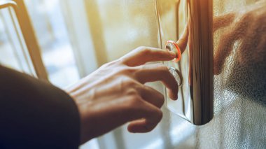 Asansör düğmesine basan. Parmak asansör düğmesine basar. Kırmızı düğme. gün batımı ışığı.