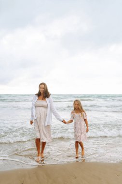 Hamile kadın ve kız gün batımında sahilde gezinirler. Bebek bekleyen genç bir anne, doğada büyük kızıyla vakit geçirir. Aile kavramı, birlikte geçirdiğimiz zaman ve hamilelik..