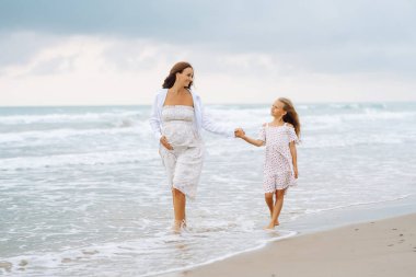 Hamile kadın ve kız gün batımında sahilde gezinirler. Bebek bekleyen genç bir anne, doğada büyük kızıyla vakit geçirir. Aile kavramı, birlikte geçirdiğimiz zaman ve hamilelik..