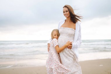 Hamile kadın ve kız gün batımında sahilde gezinirler. Bebek bekleyen genç bir anne, doğada büyük kızıyla vakit geçirir. Aile kavramı, birlikte geçirdiğimiz zaman ve hamilelik..