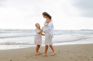 Hamile kadın ve kız gün batımında sahilde gezinirler. Bebek bekleyen genç bir anne, doğada büyük kızıyla vakit geçirir. Aile kavramı, birlikte geçirdiğimiz zaman ve hamilelik..