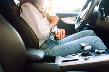 Direksiyondaki genç bir kadın emniyet kemerini bağlıyor. Bir kadın sürücü güvenlik önlemlerini izler ve arabada otururken emniyet kemerini bağlar. Ulaşım ve eğlence kavramı.