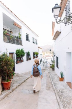 Sırt çantası ve şapkası olan bir turist gün batımında şehrin mimarisine hayran kalır. Güzel bir kadın güneşli bir caddede geziniyor. Turizm, hafta sonları ve tatil kavramları.
