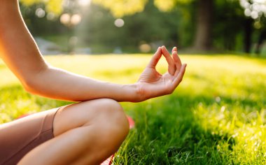 Neşeli bir kadın güneşli bir parkta minder üzerinde yoga yapıyor. Spor elbiseli bir kadın meditasyon yapar, dinlenir ya da zen 'i dışarıda bulur. Meditasyon, rahatlama kavramları.