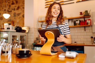 Kadın bir barista tezgahın arkasında duruyor, taze demlenmiş kahve servis ediyor. Önlüklü mutlu bir kadın sıcak bir kahve dükkanında aromatik kahve hazırlar. Küçük işletme konsepti, içkiler.
