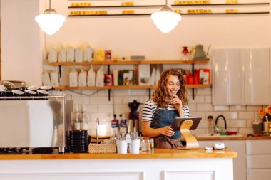 Kadın bir barista tezgahın arkasında duruyor, taze demlenmiş kahve servis ediyor. Önlüklü mutlu bir kadın sıcak bir kahve dükkanında aromatik kahve hazırlar. Küçük işletme konsepti, içkiler.