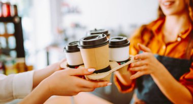 Güneşli bir günde barda elinde dijital tabletle bir kafede duran genç bir kadının portresi. Sıcak bir kahve dükkanında çalışan bayan bir barista. Küçük iş konsepti, içecekler ve teknoloji.