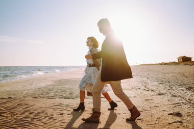 Şık genç bir çift gün batımında plaj boyunca birlikte dolaşır. Genç kadın ve erkek güneş ışınlarında deniz manzarasının özgürlüğünün tadını çıkarıyorlar. Aşkın, doğanın ve rahatlamanın kavramsal görüntüleri..