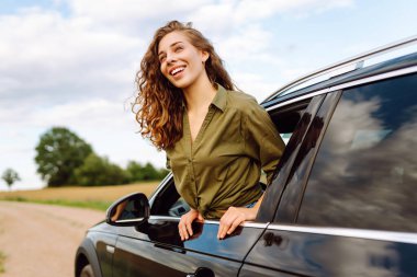 Güzel bir kadın araba camından sarkmış güneşli bir günün tadını çıkarıyor. Genç gezgin açık havanın özgürlüğünü hissediyor. Boş zaman ve ulaşım kavramı.