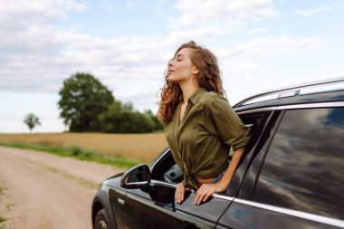 Güzel bir kadın araba camından sarkmış güneşli bir günün tadını çıkarıyor. Genç gezgin açık havanın özgürlüğünü hissediyor. Boş zaman ve ulaşım kavramı.