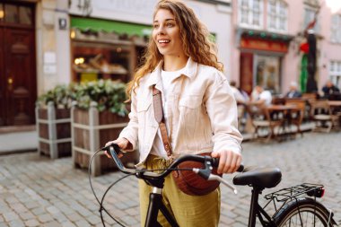 Genç bir turist, şehirde bisikletli güneşli bir günün tadını çıkarıyor. Güzel bir kadın eski kasabada bisiklet sürüyor. Konsept: ulaşım, turizm, yaşam tarzı.