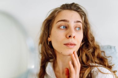 Güneşli bir odada küçük bir aynası olan genç bir kadının portresi. Güzel bir kadın sıcacık bir yerde yansımasına hayran olur. Kavram: güzellik, kozmetoloji.