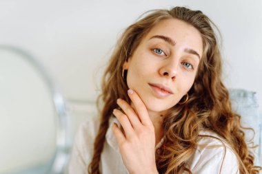 Güneşli bir odada küçük bir aynası olan genç bir kadının portresi. Güzel bir kadın sıcacık bir yerde yansımasına hayran olur. Kavram: güzellik, kozmetoloji.