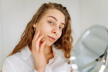 Güneşli bir odada küçük bir aynası olan genç bir kadının portresi. Güzel bir kadın sıcacık bir yerde yansımasına hayran olur. Kavram: güzellik, kozmetoloji.