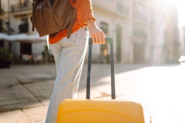 Güneşli bir sokakta parlak bir sırt çantasında bir turistin elinin yakın çekimi. Sırt çantalı genç bir kadın eski kasabada gezintiden hoşlanıyor. Seyahat ve eğlence kavramları.