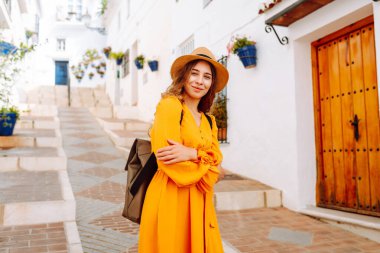 Sarı elbiseli ve şapkalı mutlu bir turist şehrin eski, güneşli caddelerinde geziniyor. Güzel bir kadın gün batımından zevk alır. Turizm kavramı, hafta sonu, dinlenme.