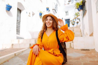 Sarı elbiseli ve şapkalı mutlu bir turist şehrin eski, güneşli caddelerinde geziniyor. Güzel bir kadın gün batımından zevk alır. Turizm kavramı, hafta sonu, dinlenme.