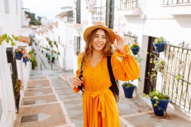 Sarı elbiseli ve şapkalı mutlu bir turist şehrin eski, güneşli caddelerinde geziniyor. Güzel bir kadın gün batımından zevk alır. Turizm kavramı, hafta sonu, dinlenme.