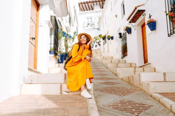 Sarı elbiseli ve şapkalı mutlu bir turist şehrin eski, güneşli caddelerinde geziniyor. Güzel bir kadın gün batımından zevk alır. Turizm kavramı, hafta sonu, dinlenme.