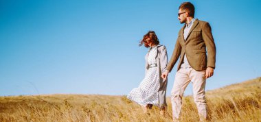 Birbirine aşık genç bir çift güneş ışınlarıyla çimenli bir tarlada geziniyor. Şık bir erkek ve kadın birlikte vakit geçirir, gün batımının tadını çıkarırlar. Aşk, tarz ve moda kavramı.