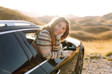 Güzel bir gezgin araba camından dışarı bakar ve dağ manzarasına hayran kalır. Genç kadın kendini özgür hissediyor, gün batımında bir yol gezisinde rüzgarı saçlarıyla yakalıyor. Macera kavramı, özgürlük..