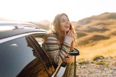Güzel bir gezgin araba camından dışarı bakar ve dağ manzarasına hayran kalır. Genç kadın kendini özgür hissediyor, gün batımında bir yol gezisinde rüzgarı saçlarıyla yakalıyor. Macera kavramı, özgürlük..