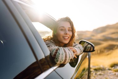 Güzel bir gezgin araba camından dışarı bakar ve dağ manzarasına hayran kalır. Genç kadın kendini özgür hissediyor, gün batımında bir yol gezisinde rüzgarı saçlarıyla yakalıyor. Macera kavramı, özgürlük..