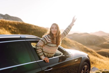 Güzel bir gezgin araba camından dışarı bakar ve dağ manzarasına hayran kalır. Genç kadın kendini özgür hissediyor, gün batımında bir yol gezisinde rüzgarı saçlarıyla yakalıyor. Macera kavramı, özgürlük..