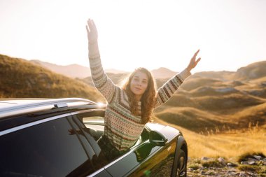 Güzel bir gezgin araba camından dışarı bakar ve dağ manzarasına hayran kalır. Genç kadın kendini özgür hissediyor, gün batımında bir yol gezisinde rüzgarı saçlarıyla yakalıyor. Macera kavramı, özgürlük..