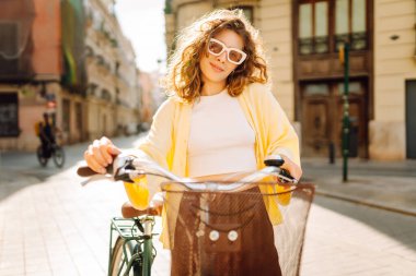 Neşeli bir kadın güneşli bir günde bisiklet sürmekten hoşlanır. Bir turist gün batımında bisiklet sürüyor, şehir sokaklarında geziniyor. Hafta sonu konsepti, turizm.