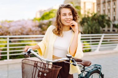 Neşeli bir kadın güneşli bir günde bisiklet sürmekten hoşlanır. Bir turist gün batımında bisiklet sürüyor, şehir sokaklarında geziniyor. Hafta sonu konsepti, turizm.