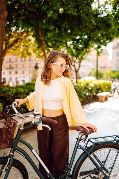 Neşeli bir kadın güneşli bir günde bisiklet sürmekten hoşlanır. Bir turist gün batımında bisiklet sürüyor, şehir sokaklarında geziniyor. Hafta sonu konsepti, turizm.