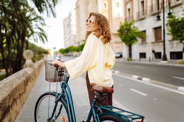 Neşeli bir kadın güneşli bir günde bisiklet sürmekten hoşlanır. Bir turist gün batımında bisiklet sürüyor, şehir sokaklarında geziniyor. Hafta sonu konsepti, turizm.
