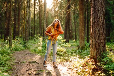 Güneşli bir ormanda yürüyüş parkurunda yürüyüş yapan sırt çantalı genç bir kadının portresi. Gezgin doğayı ve macerayı sever. Seyahat ve doğa kavramı, yürüyüş..