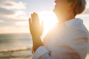 Gün batımında deniz kıyısında beyaz saçlı bir kadının portresi, deniz manzarasının tadını çıkarıyor. Yaşlı bir kadın sahilde kendini özgür hisseder. Mutlu emeklilik, rahatlama ve meditasyon kavramı.