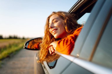 Yolculukta olan güzel bir kadın gün batımında bir arabanın camından sarkmış. Kadın geziyor, kırsal manzaranın tadını çıkarıyor ve güneşli bir günde kendini özgür hissediyor. Ulaşım ve özgürlük kavramı.