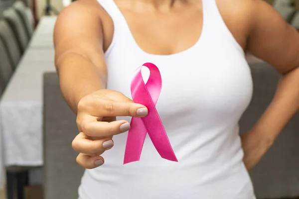 Young woman, with pink t-shirt, holding pink ribbon, preventing aids.