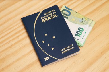 Pasaportun yanında 100 Euro 'luk banknotlar, ahşap masa..