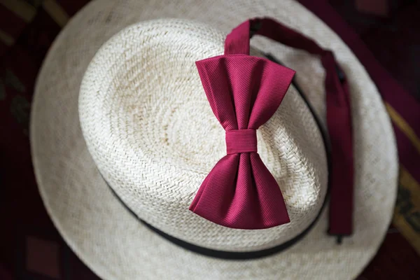 Red male bow-tie on a white wicker vintage hat. — Stock Photo, Image