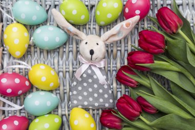 Paskalya tavşanı, kırmızı lale, boyalı yumurta Hasır arka plan üzerinde renkli