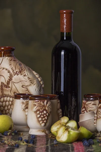 Mesa folclórica con alfombra étnica, vino dulce, jarra, vasos, manzanas — Foto de Stock