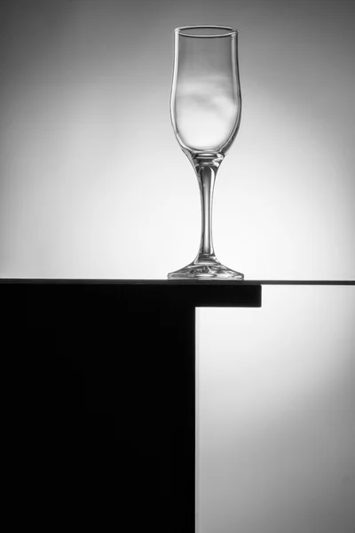 Composizione in bianco e nero con bicchiere da vino vuoto su un tavolo . — Foto Stock