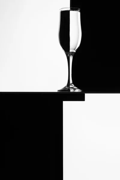 Composizione in bianco e nero con bicchiere da vino vuoto su un tavolo . — Foto Stock